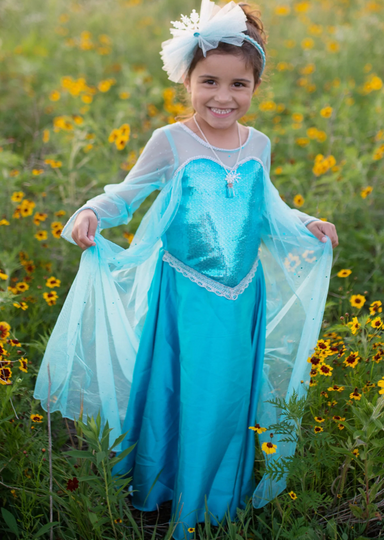 Young girl in a sparkly blue princess dress standing in a field of yellow flowers
