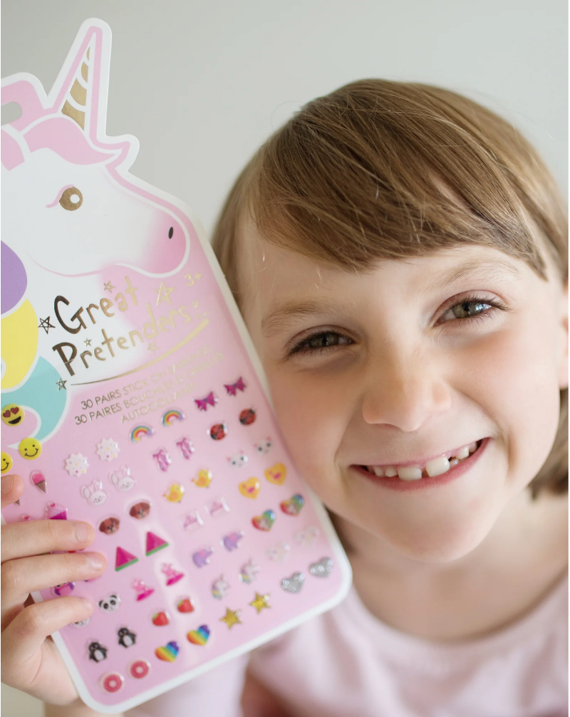 child holding unicorn-shaped card containing 30 pairs of stick on earrings in Hearts, stars, rainbows and more designs