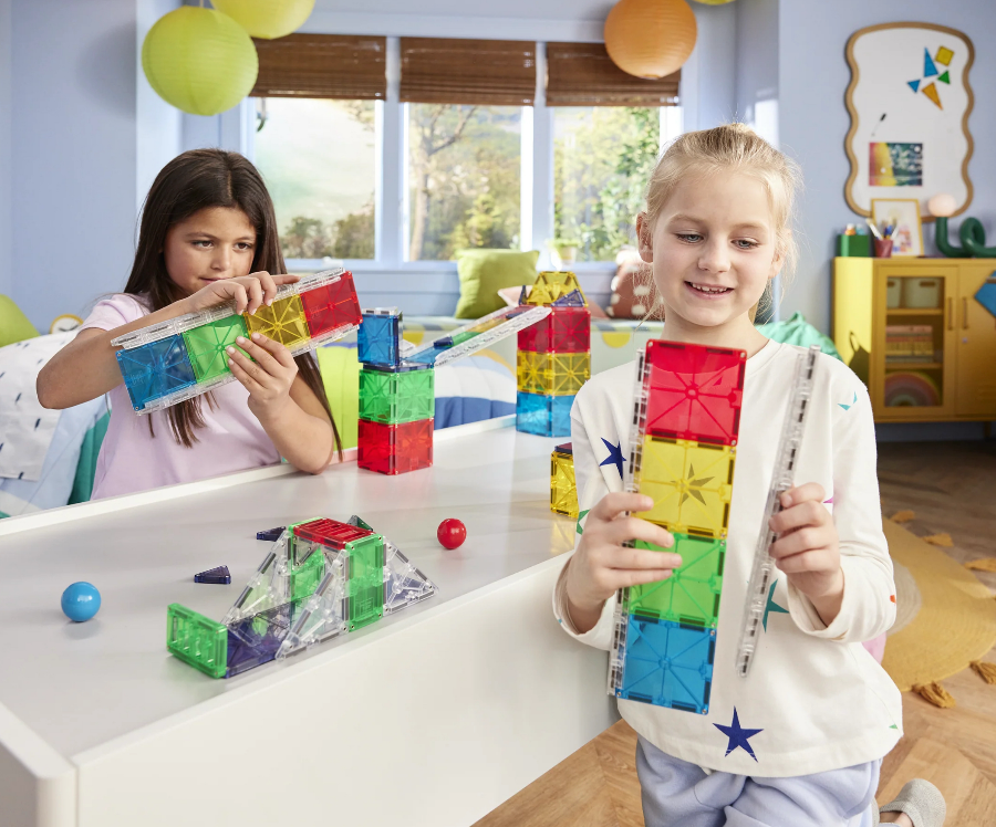 Two children playing with colorful building blocks in a bright room.