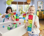 Two children playing with colorful building blocks in a bright room.
